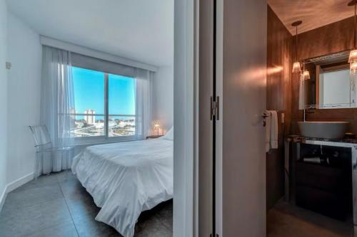 a bedroom with a bed and a bathroom with a window at Apartamento en Punta del Este Uruguay in Punta del Este