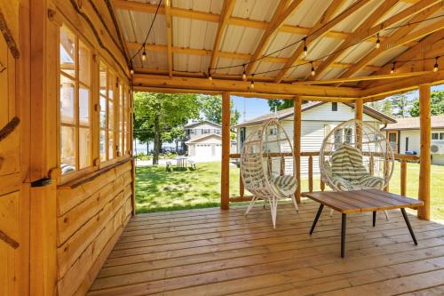 a wooden porch with two chairs and a table at Chippewa Bluffs Resort Combined 4BR 4BA Cabins in Barryton