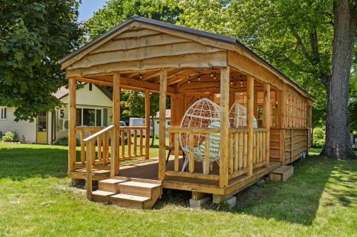 a wooden gazebo with a swing in a yard at Chippewa Bluffs Resort Combined 4BR 4BA Cabins in Barryton