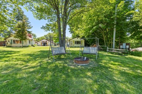 two swings in a yard with a tree at Chippewa Bluffs Resort Combined 4BR 4BA Cabins in Barryton