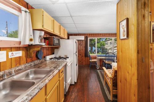 a kitchen with a sink and a refrigerator at Chippewa Bluffs Resort Combined 4BR 4BA Cabins in Barryton