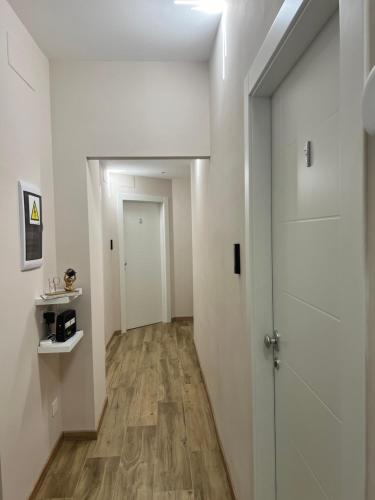 a hallway with white walls and a door and wooden floors at Raffaelli Suite in Rome