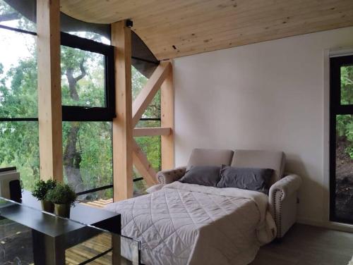 a bedroom with a bed and a table and windows at Conguillio Lava Cave in Melipeuco