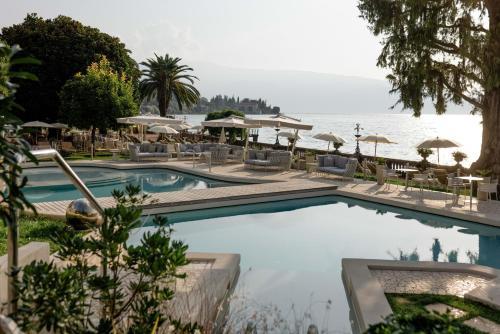 a pool with chairs and umbrellas next to the water at Grand Hotel Fasano in Gardone Riviera