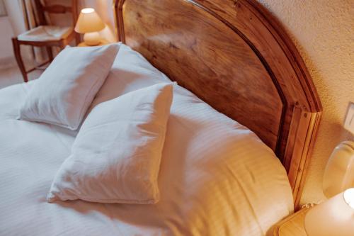 a bed with white pillows and a wooden headboard at Hôtel De France in Chalabre