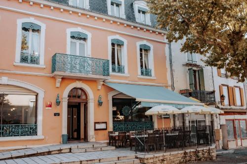 a building with tables and chairs in front of it at Hôtel De France in Chalabre