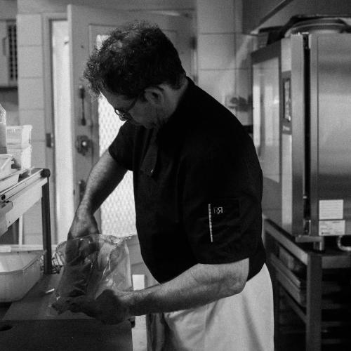 a man standing in a kitchen preparing food at Hôtel De France in Chalabre