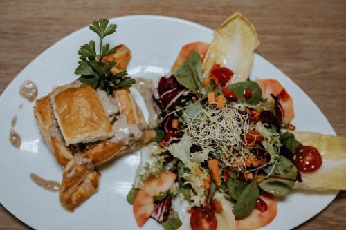 a plate of food with a salad and a sandwich at Hôtel De France in Chalabre