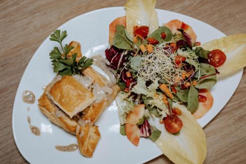 a white plate with a salad and a sandwich at Hôtel De France in Chalabre