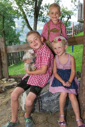 three young children sitting on a bench with a dog at Appartements Lehenhof in Sankt Johann im Pongau