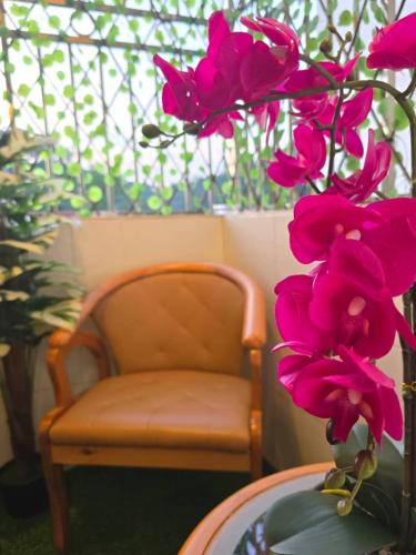 a chair and a table with pink flowers in a vase at Qaira Eco Homestay in Kota Kinabalu