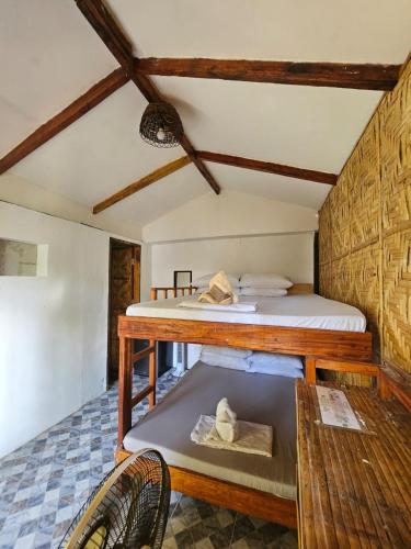 a room with a bed and a table and a bench at Big BamBoo Beach Resort Sipalay in Sipalay