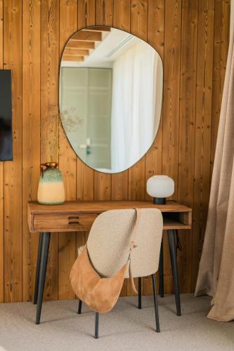 a mirror on a wooden wall with a desk and a chair at The Pines Bucegi Lodge in Bran