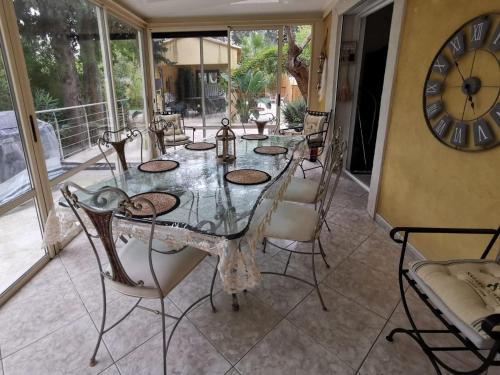 a dining room with a table and chairs and a clock at Maison de Charme en couleurs in Cuers