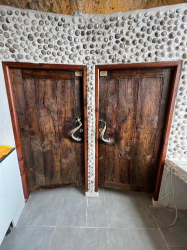 two wooden doors in a room with a wall at Casa Rural Cueva Las Varas in El Mudo