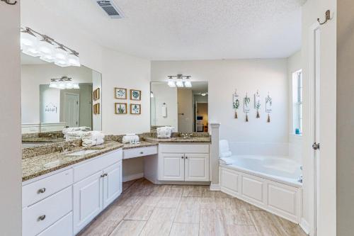 Un baño blanco con dos lavabos y una bañera. en Casa Palmera, en Pensacola