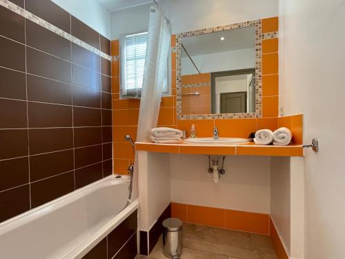 Un baño con lavabo, bañera y espejo. en Villa Verdi, en Montauroux