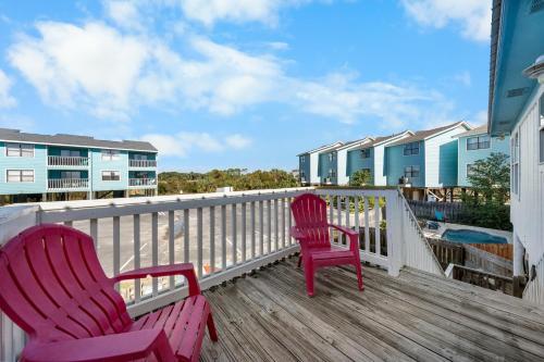 two red chairs sitting on a deck with the beach at Surfs Up in Gulf Shores