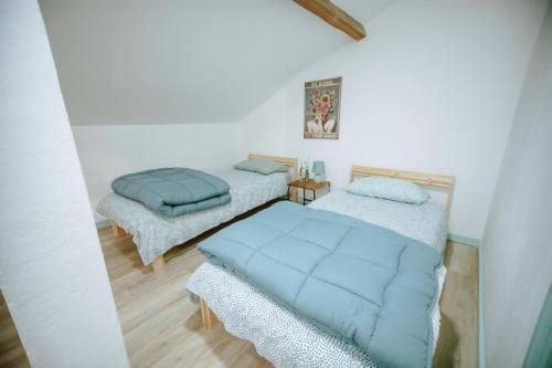 two beds in a white room with blue blankets at Poolemonhouse in Fernao Ferro