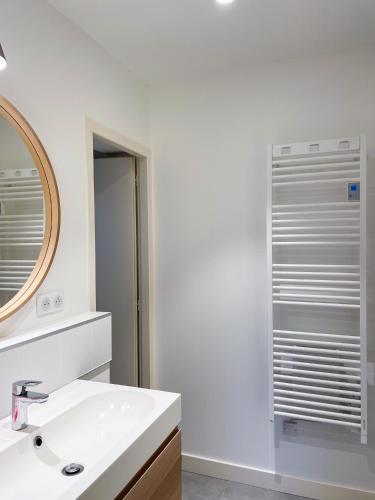 une salle de bain blanche avec un lavabo et un miroir dans l'établissement Dolce - Petite maison basque rénovée, à Biarritz