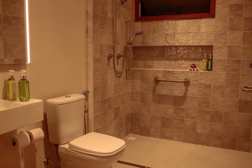a bathroom with a toilet and a shower at AL MAR SUÍTES in Praia do Forte
