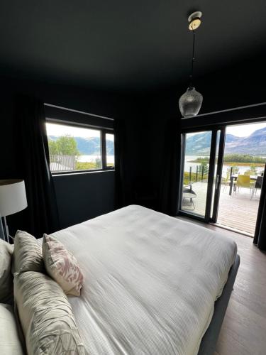 une chambre avec un grand lit blanc avec une grande fenêtre dans l'établissement Efjord and Stetind Resort - Cabin Stetind, à Ballangen