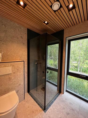 La salle de bains est pourvue d'une douche, de toilettes et de fenêtres. dans l'établissement Efjord and Stetind Resort - Cabin Stetind, à Ballangen