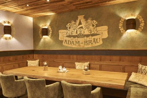a table in a restaurant with a sign on the wall at Wellness- und Bierhotel Adam Bräu in Bodenmais