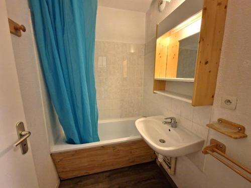 La salle de bains est pourvue d'un rideau de douche bleu et d'un lavabo. dans l'établissement Charmant 2 pièces + cabine, 4/6 pers, au cœur de Modane, 32m², proche pistes et commerces - FR-1-265-250, à Valfréjus