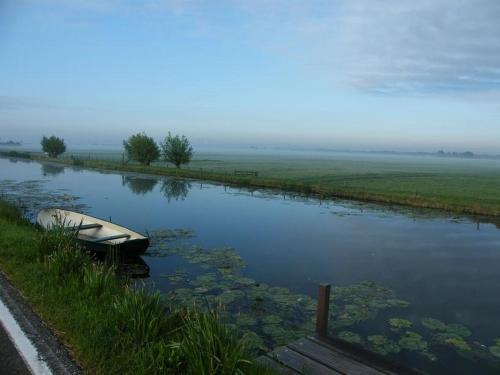 a boat sitting on the side of a river at Aan de Kwakel in Maasland