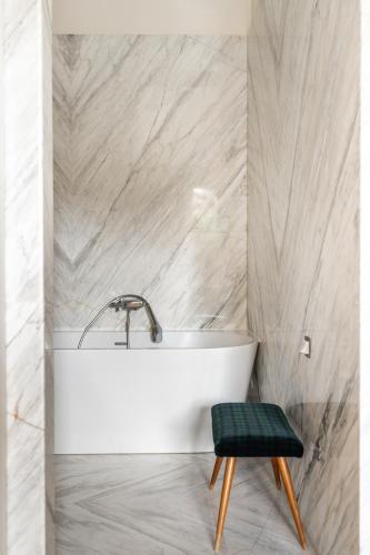 La salle de bains est pourvue d'une baignoire blanche et d'un tabouret vert. dans l'établissement Luxury apartment on Canal Saint Martin, à Paris