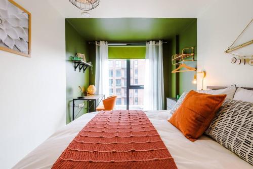 a bedroom with a white bed with orange pillows and a window at Kelham's Finest - Elegant & Comfy 2 Bedroom Flat in Sheffield