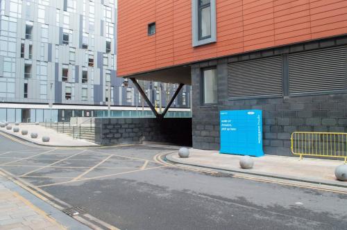 a building with a blue sign in a parking lot at Stunning Mersey View Flat W Parking In Liverpool in Liverpool
