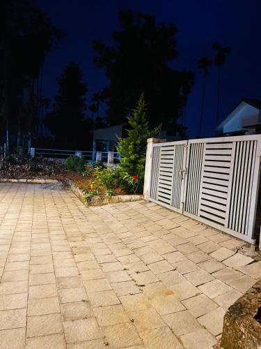 a white fence next to a concrete sidewalk at Nilaavu Homes - The Staycation at Wayanad in Panamaram