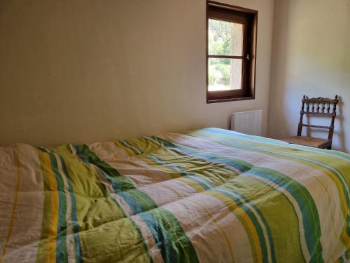 a bed in a bedroom with a window and a chair at Chalet Catalan proche des pistes in Porta