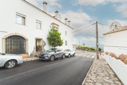 three cars parked on a street next to a white building at Apartamento Vistas y Chimenea in Benaocaz