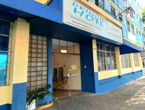 a blue and yellow building with a table in the doorway at Príncipe Hotel Maringá in Maringá
