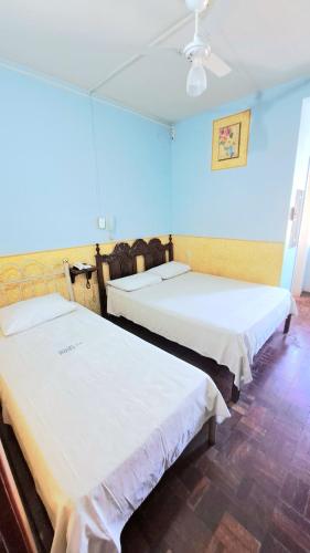 two beds in a room with blue walls at Príncipe Hotel Maringá in Maringá