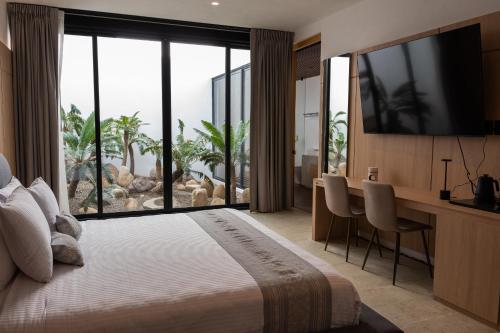 a bedroom with a large bed with a desk and a large window at Casa Carmen Xólotl in Oaxaca City