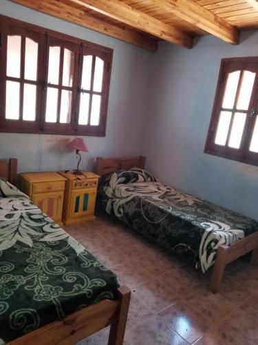 a room with two beds and a table and windows at Centro Ecoholístico Alami in San Marcos Sierras