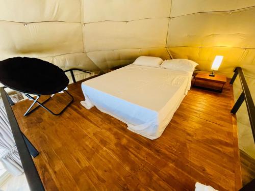 a bedroom with a bed and a table and a chair at Serenity Glampings Quinta Montaña in Cóbano