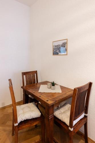 a wooden table with two chairs and a table with a plant on it at Gästehaus am Winckel in Stendal