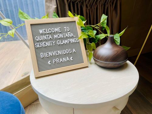 a sign sitting on top of a table with a vase at Serenity Glampings Quinta Montaña in Cóbano