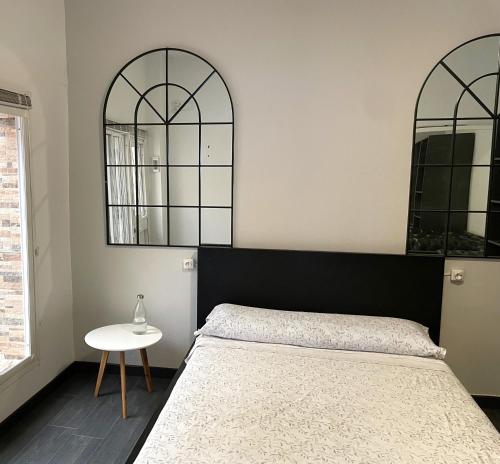 a bedroom with a bed and two mirrors on the wall at Apartamento Plaza del Cabildo - Sanlúcar Centro in Sanlúcar de Barrameda