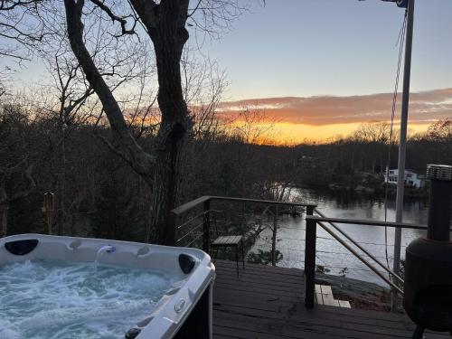 a hot tub on a deck with a view of a river at Waterfront Lakehouse Getaway in Clinton with HOT TUB in Clinton