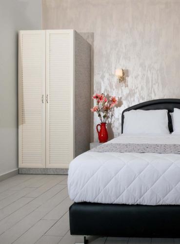 a bedroom with a bed and a red vase with flowers at Hotel Alma - Near The Sea in Netanya