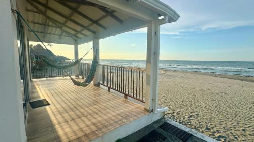 a porch with a hammock on the beach at Hermosa Cabaña Frente Al Mar in San Bernardo del Viento