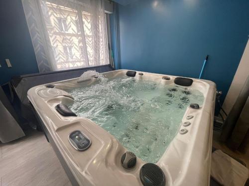 une baignoire remplie d'eau devant une fenêtre dans l'établissement Résidence Relaxante Jacuzzi - 041, à Rouen