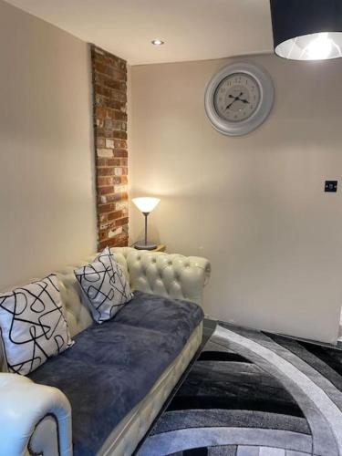 a couch in a living room with a clock on the wall at Flat 3 Meadow View Cozy Getaway in Hurst