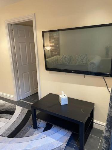 a living room with a black table and a flat screen tv at Flat 3 Meadow View Cozy Getaway in Hurst